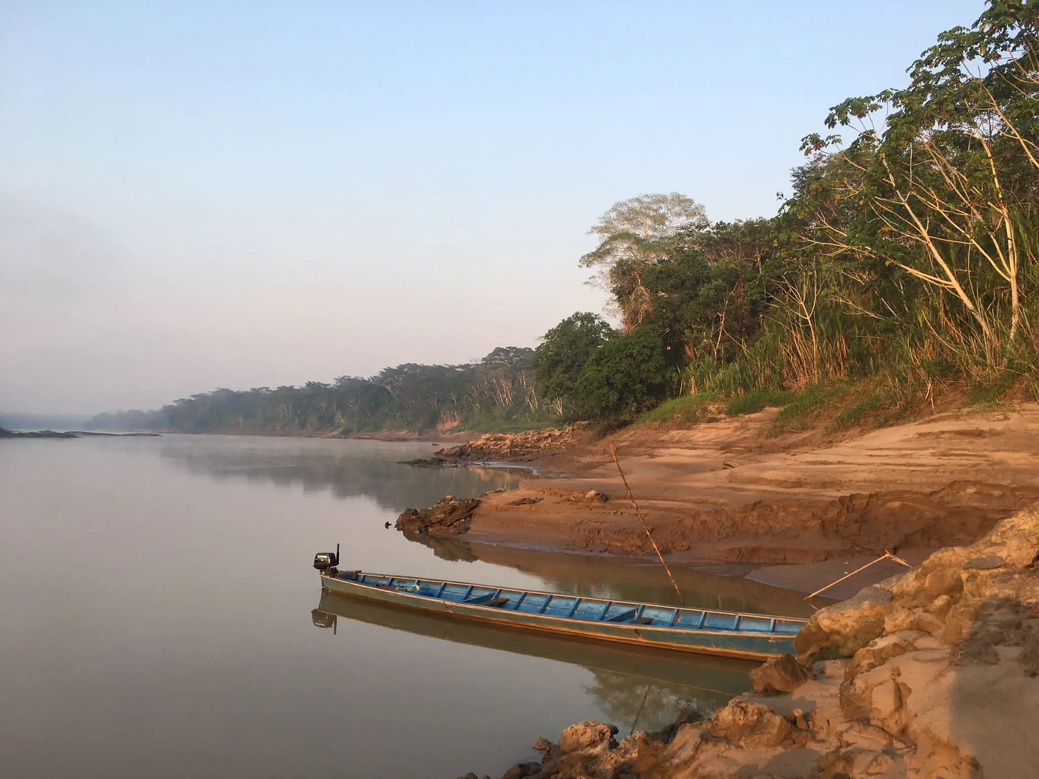 A wooden boat resting on the Amazon River at dawn