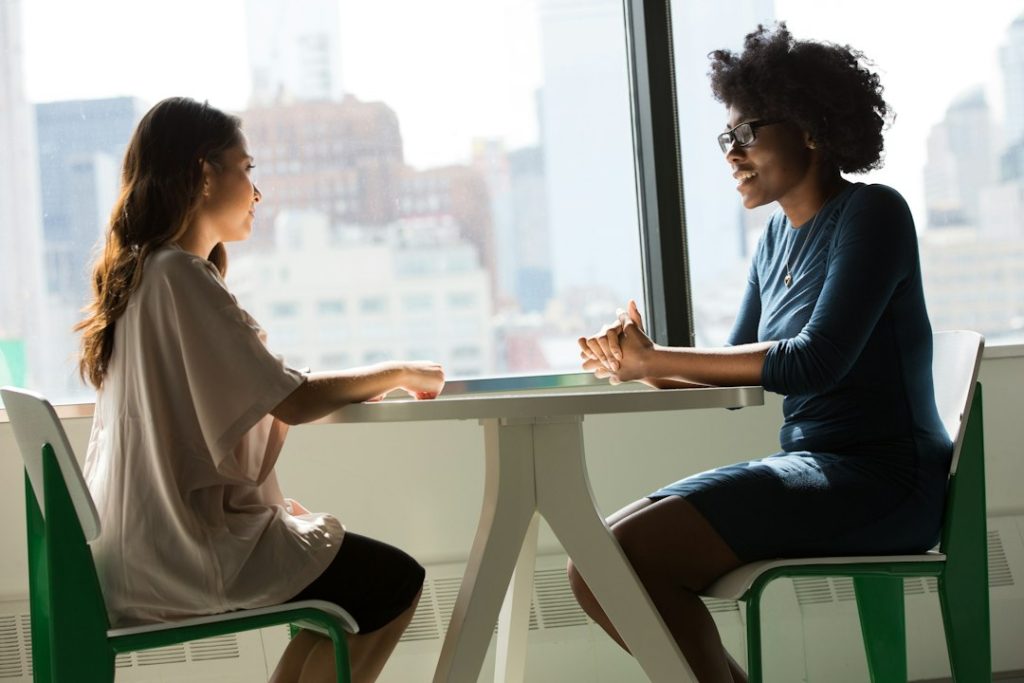 Two women seated across from each other in a thoughtful conversation