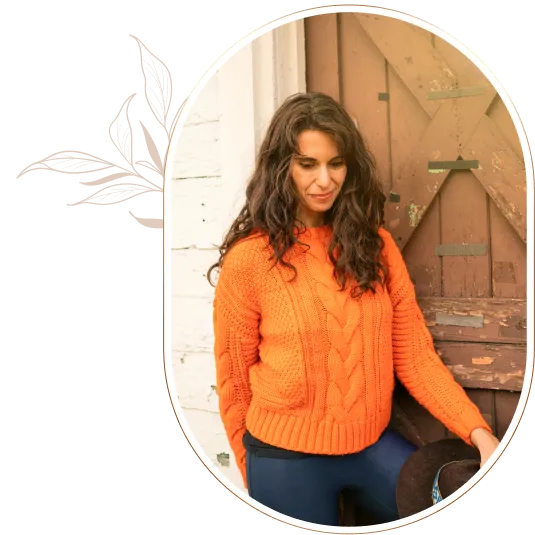 Sofia Zilberman in an orange sweater, looking inward beside a wooden doorway